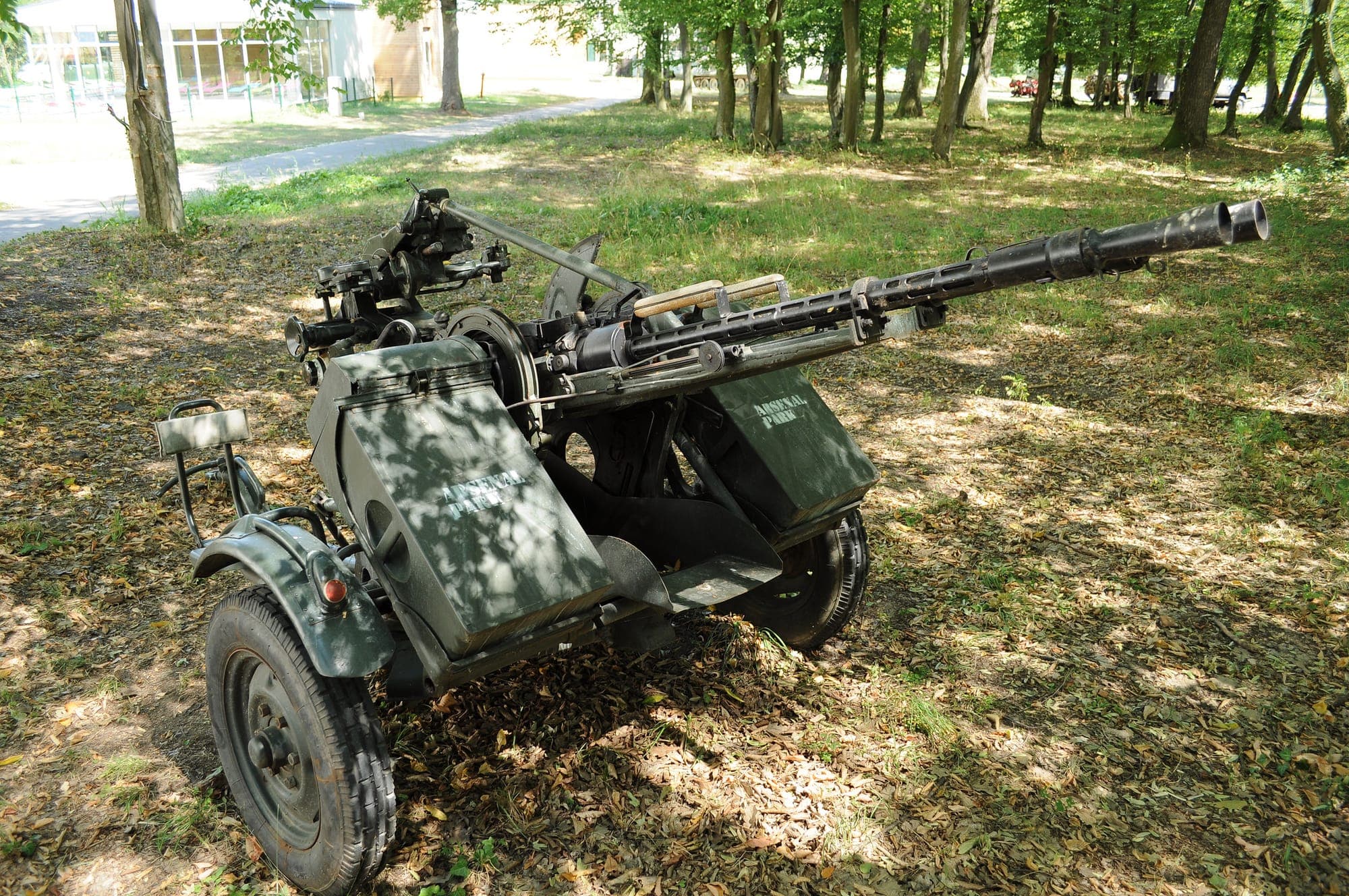 Ein doppelläufiges Fliegerabwehr-Maschinengewehr ZU-2 auf einer Radlafette, zwischen Bäumen, mit einem Weg im Hintergrund