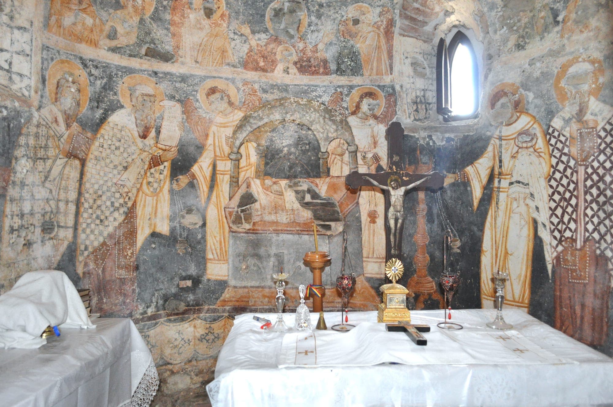 Absida altarului cu picturi medievale: ierarhi în odăjdii, îngeri și Sfântul Mormânt în arcadă, în spatele mesei de altar