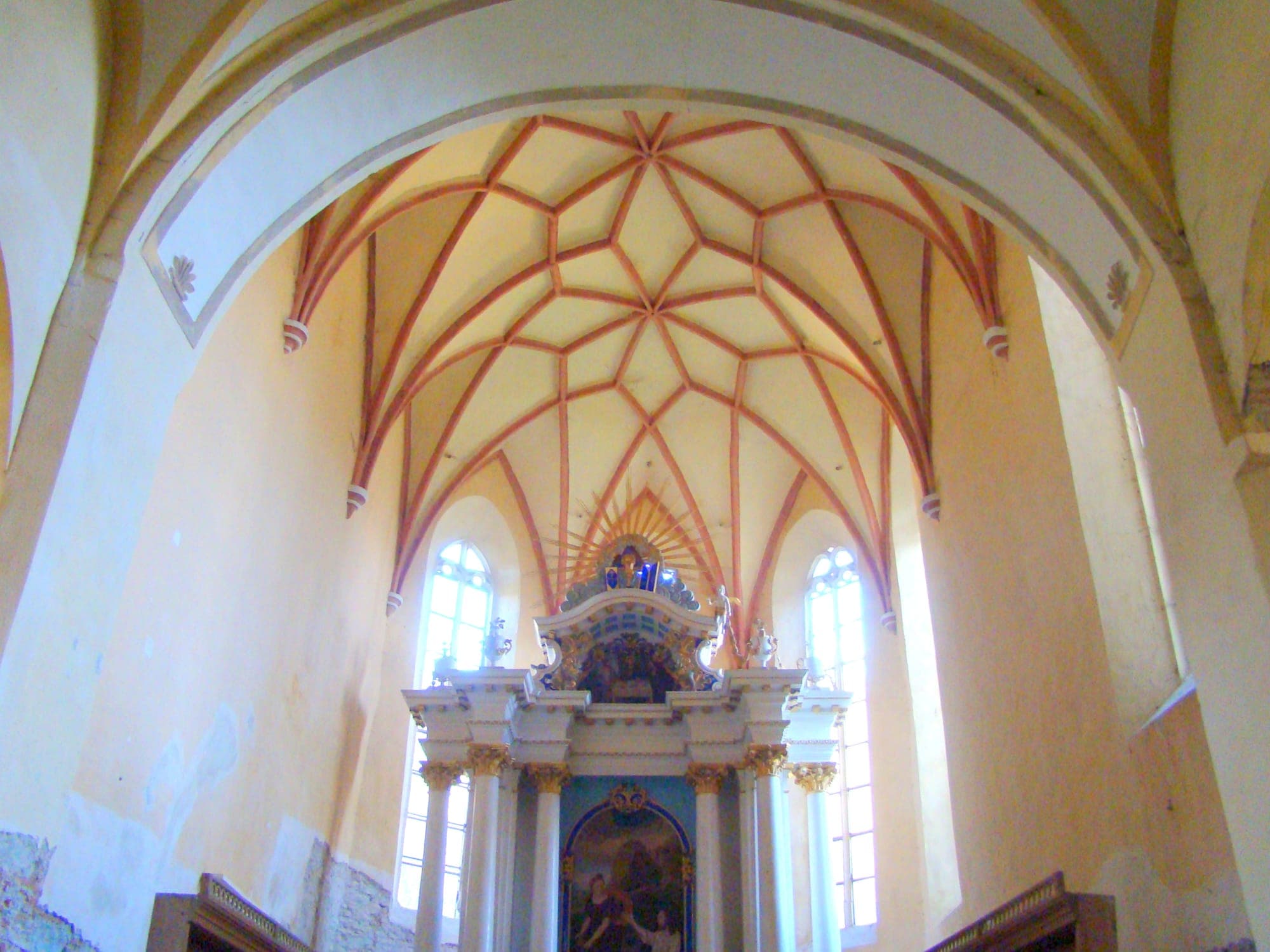 Der Chor mit dem Sterngewölbe mit unverputzten Backsteinrippen, den gotischen Seitenfenstern und dem klassizistischen Altar mit Säulen