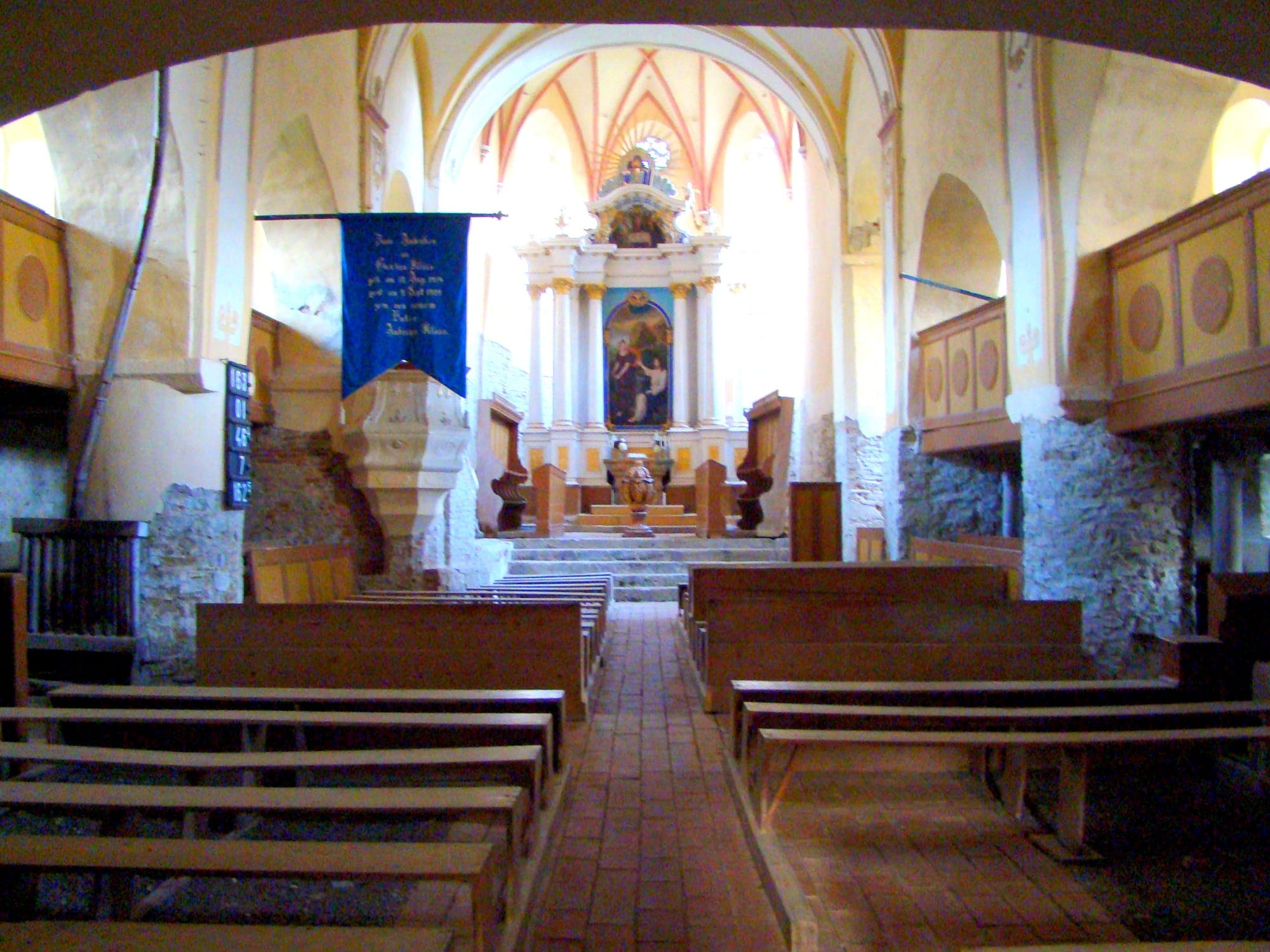 Das Schiff mit Blick zum Altar, mit Holzbänken, der Kanzel und dem hellen Chor im Hintergrund