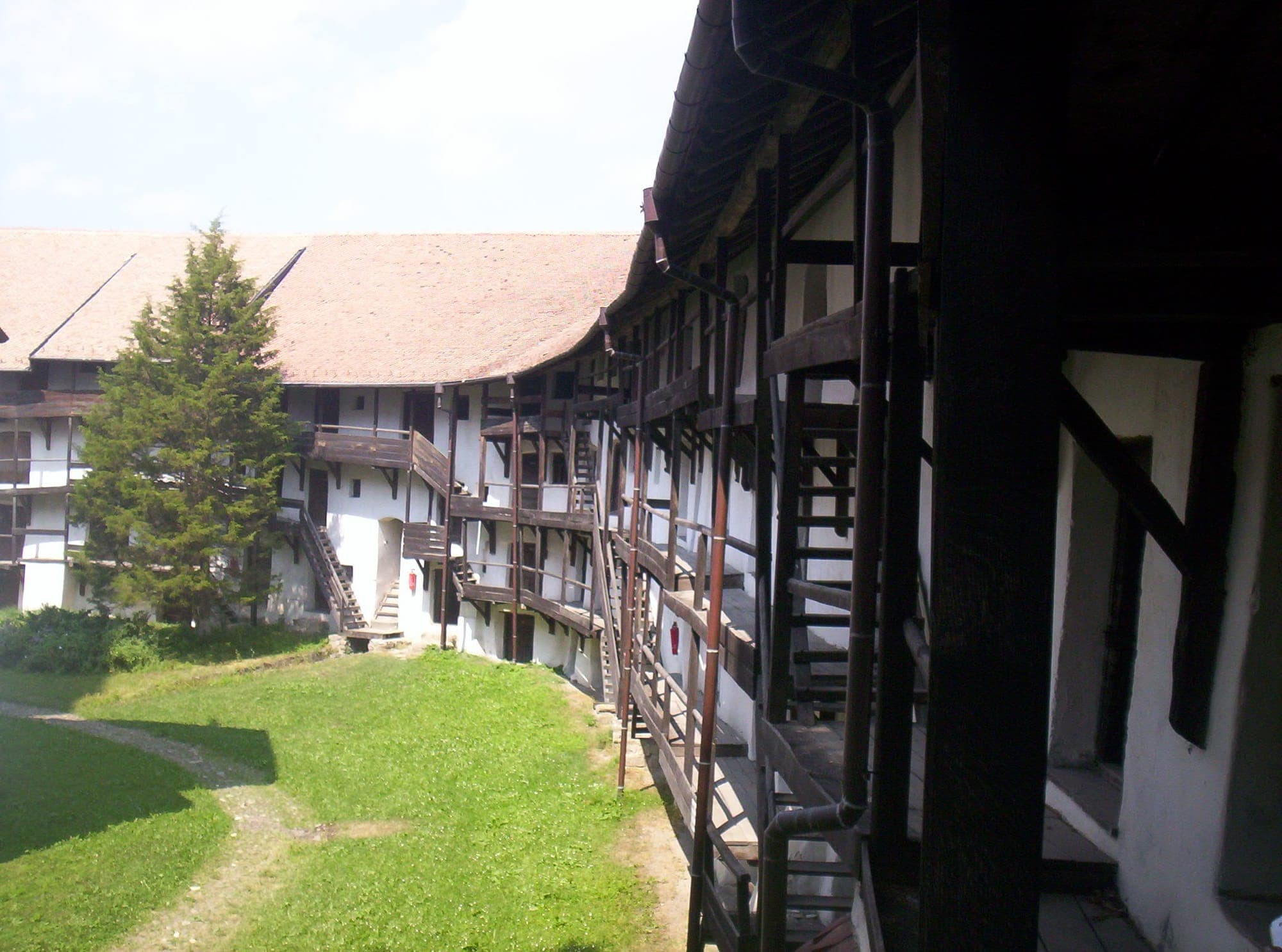 The grassy inner courtyard, surrounded by storerooms on several levels with timber stairs and galleries