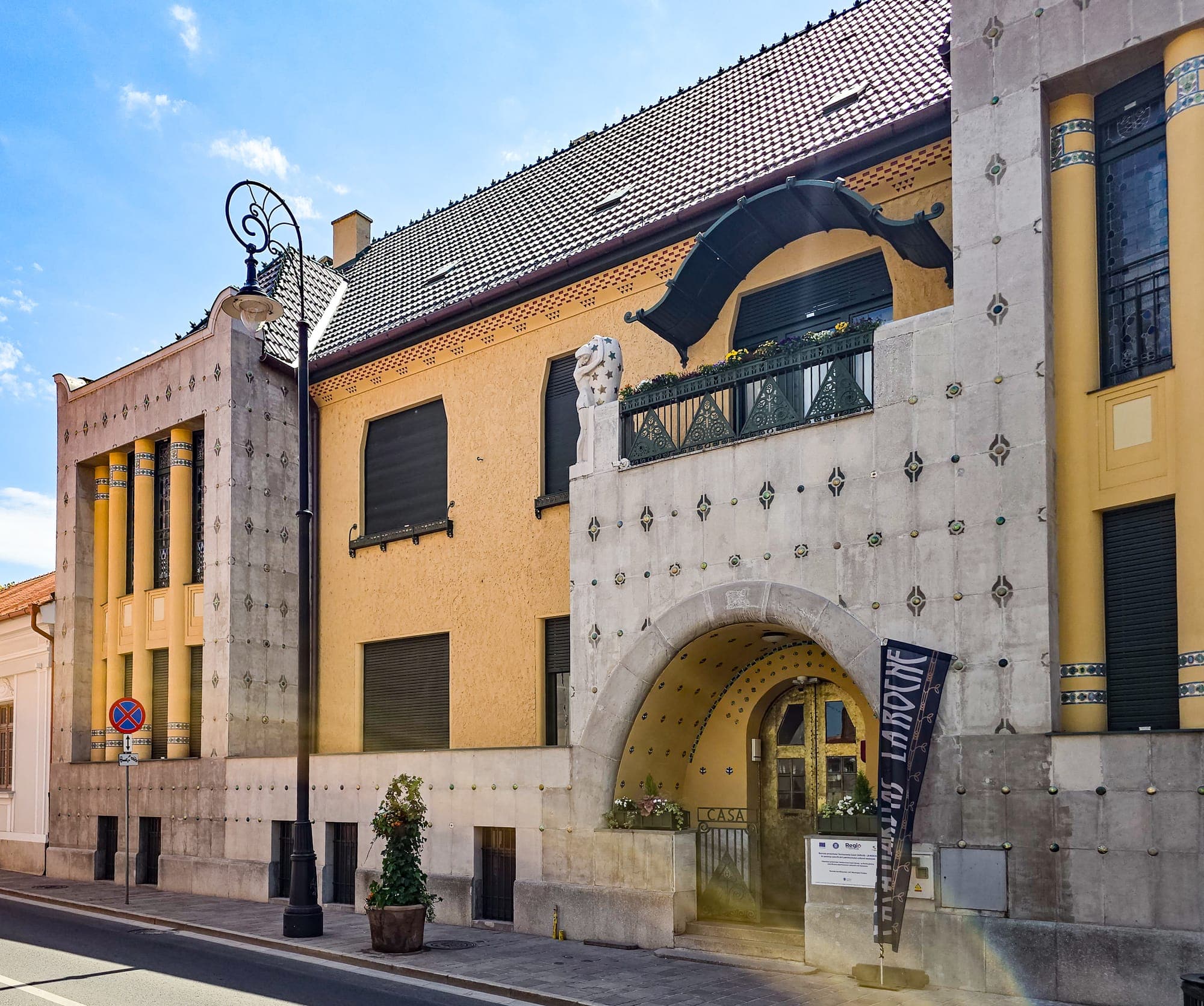 La facciata principale di Casa Darvas-La Roche, con pannelli decorati da bottoni di ceramica, l'arco d'ingresso e le finestre tra colonne gialle