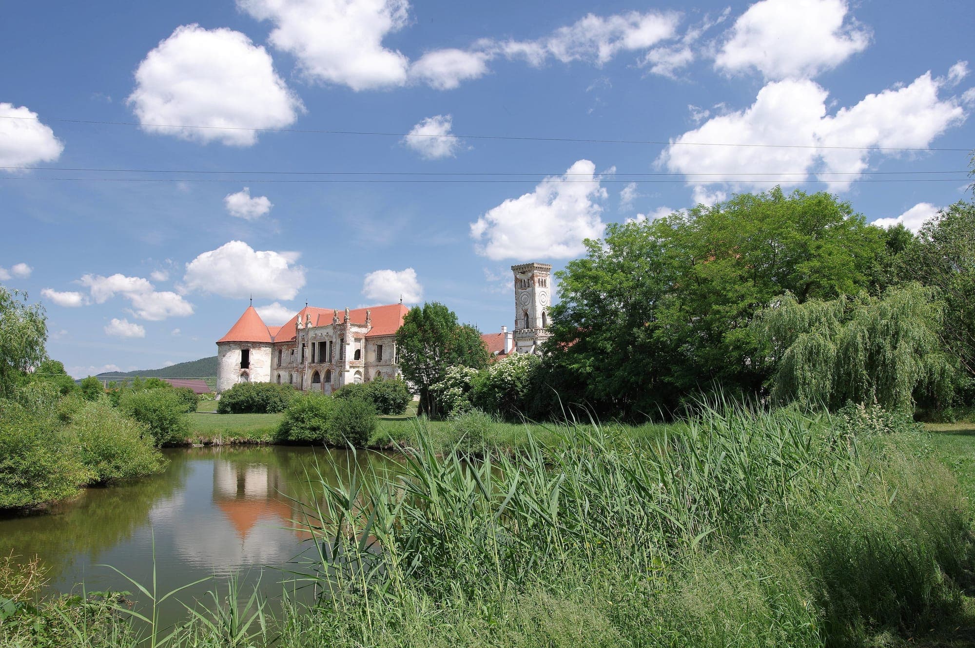 Castelul și turnul fostei bucătării oglindite în lacul din parc