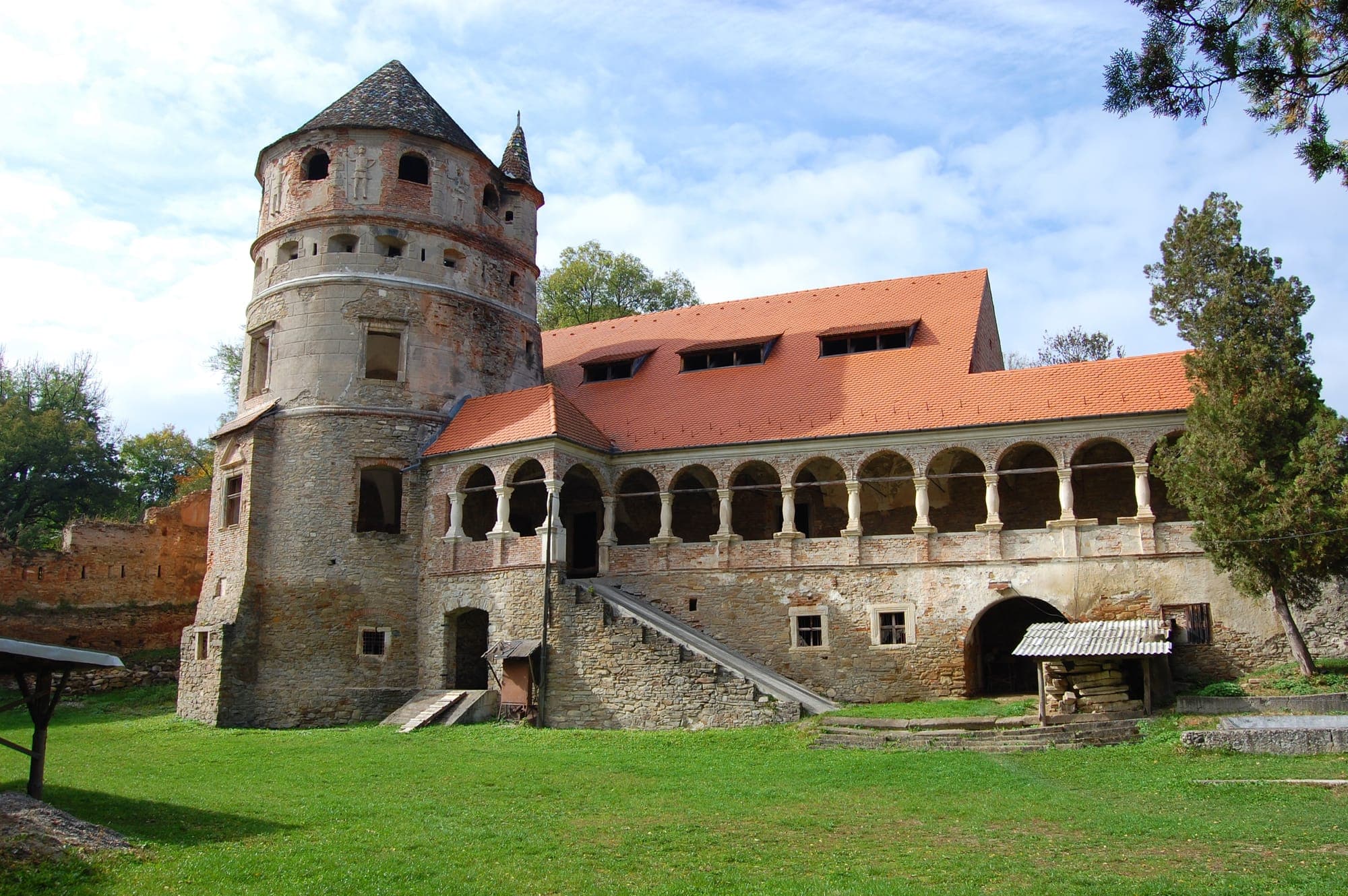 Turnul rotund și loggia cu arcade a castelului, văzute din curtea cu iarbă