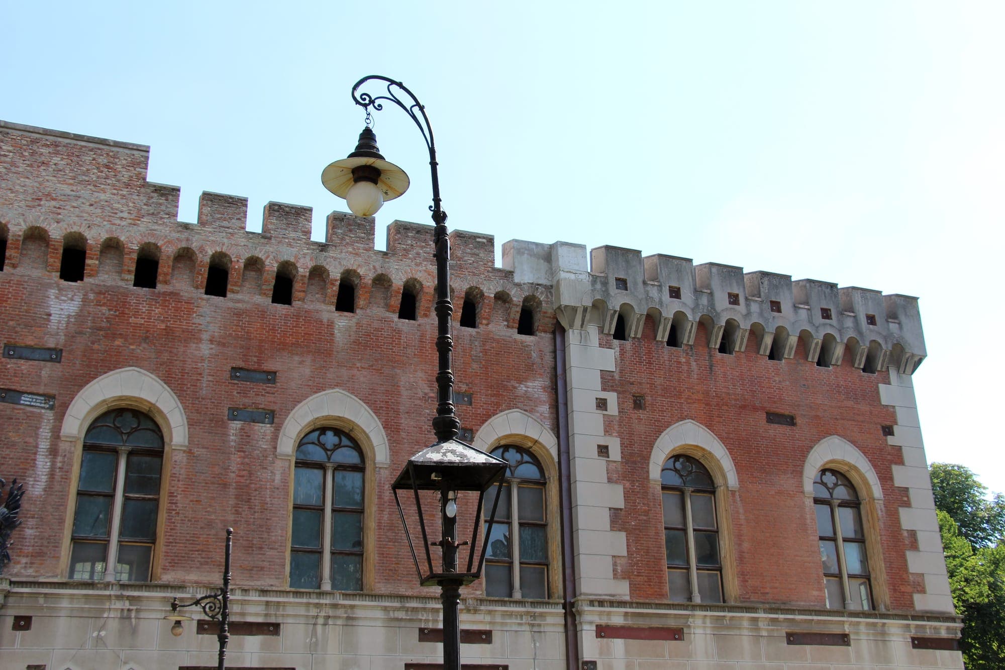 Façade detail: pointed-arch windows with white surrounds and brick-arcaded crenellations