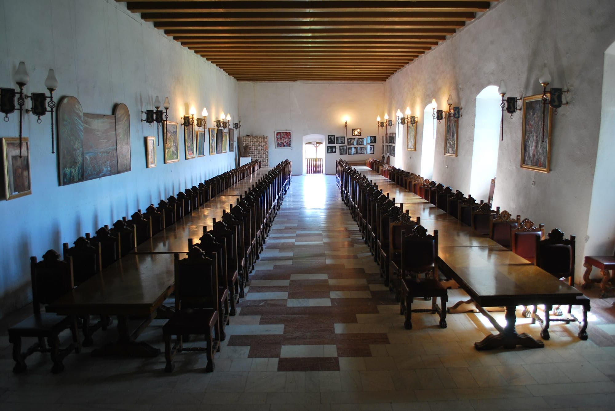 Sala Cavalerilor, cu tavan de grinzi, două șiruri de mese lungi cu scaune sculptate și tablouri pe pereți