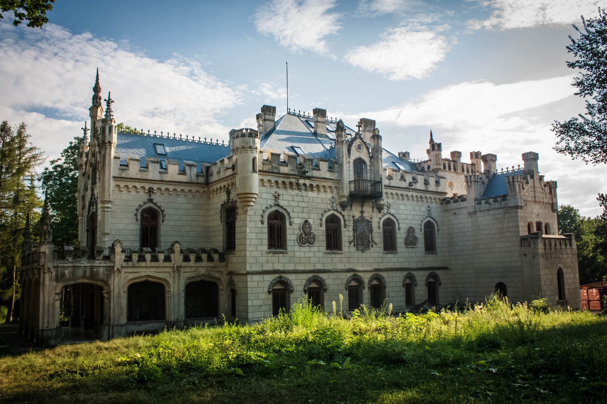 Castelul văzut din lateral, cu acoperișul, turnulețele și terasa cu arcade, sub un cer cu nori