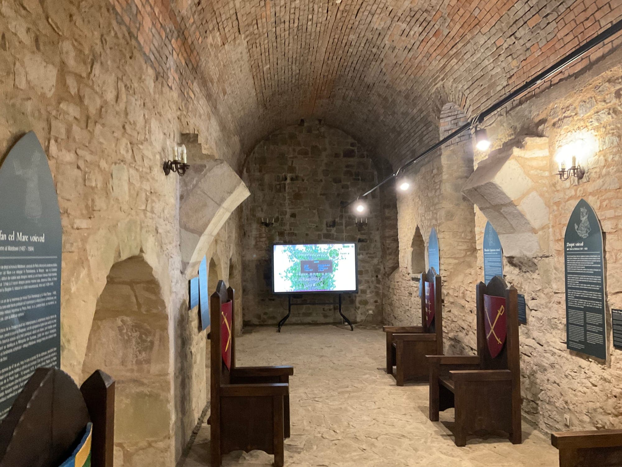 Sala Voievozilor, o sală boltită din piatră cu tronuri de lemn aliniate și panouri cu stemele domnilor