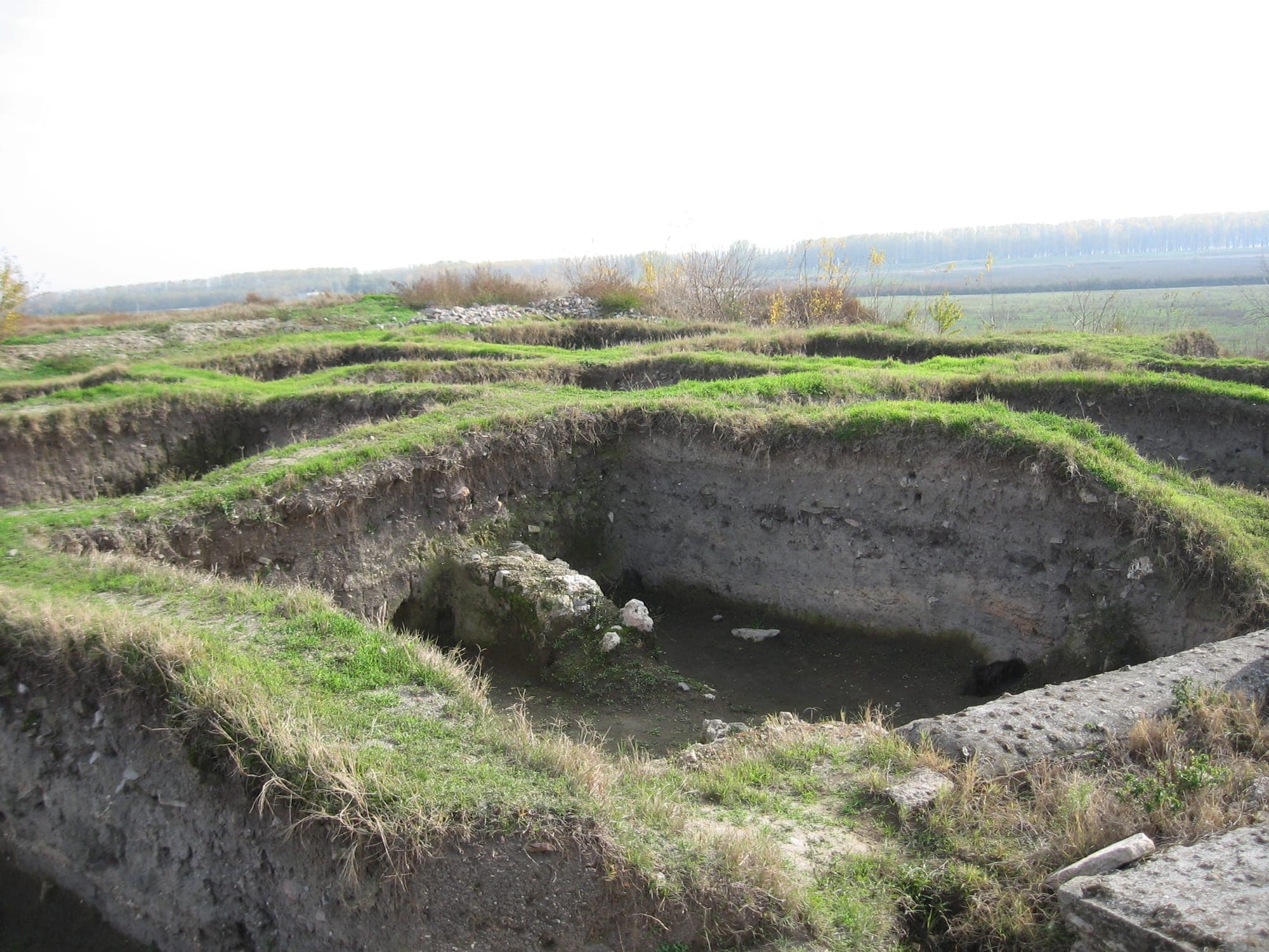 Grasbewachsene Grabungsgräben auf der Terrasse der Festung, mit der Donauaue im Hintergrund