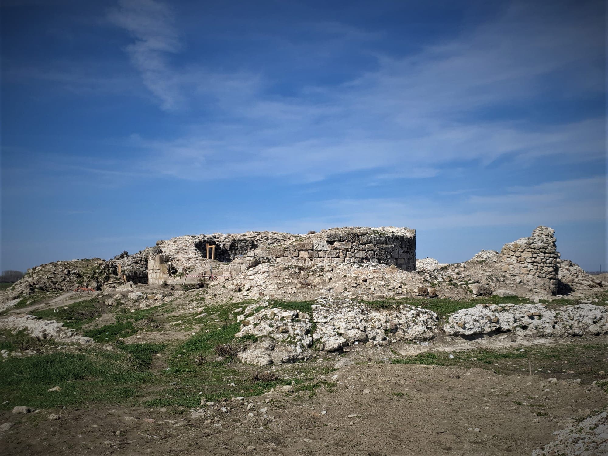 The fortress ruins in 2019, before the works were finished, with the central tower and a stretch of wall on the right, under a blue sky