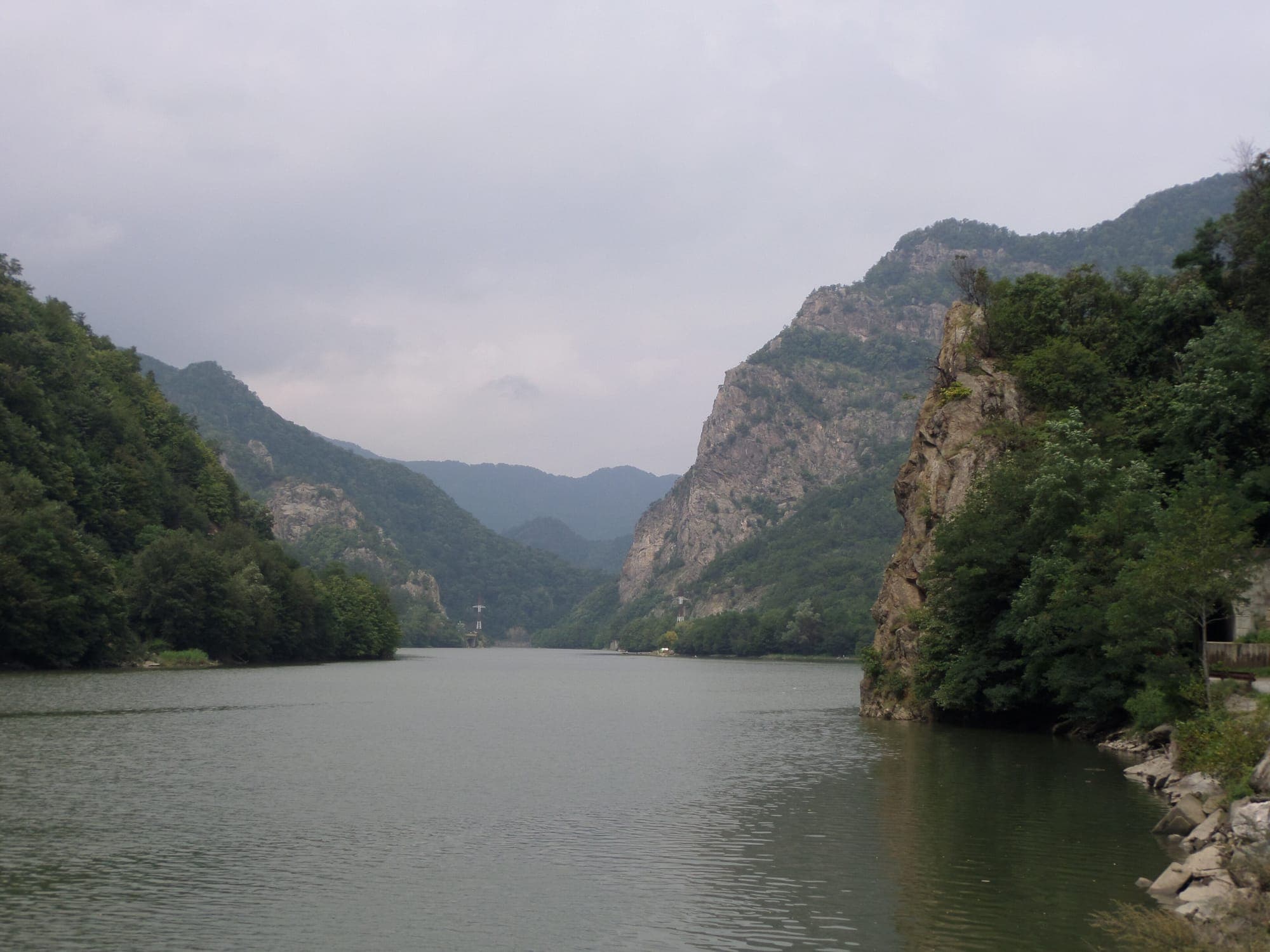 Oltul strâns între versanți împăduriți și pereți de stâncă, în Defileul Oltului din județul Vâlcea