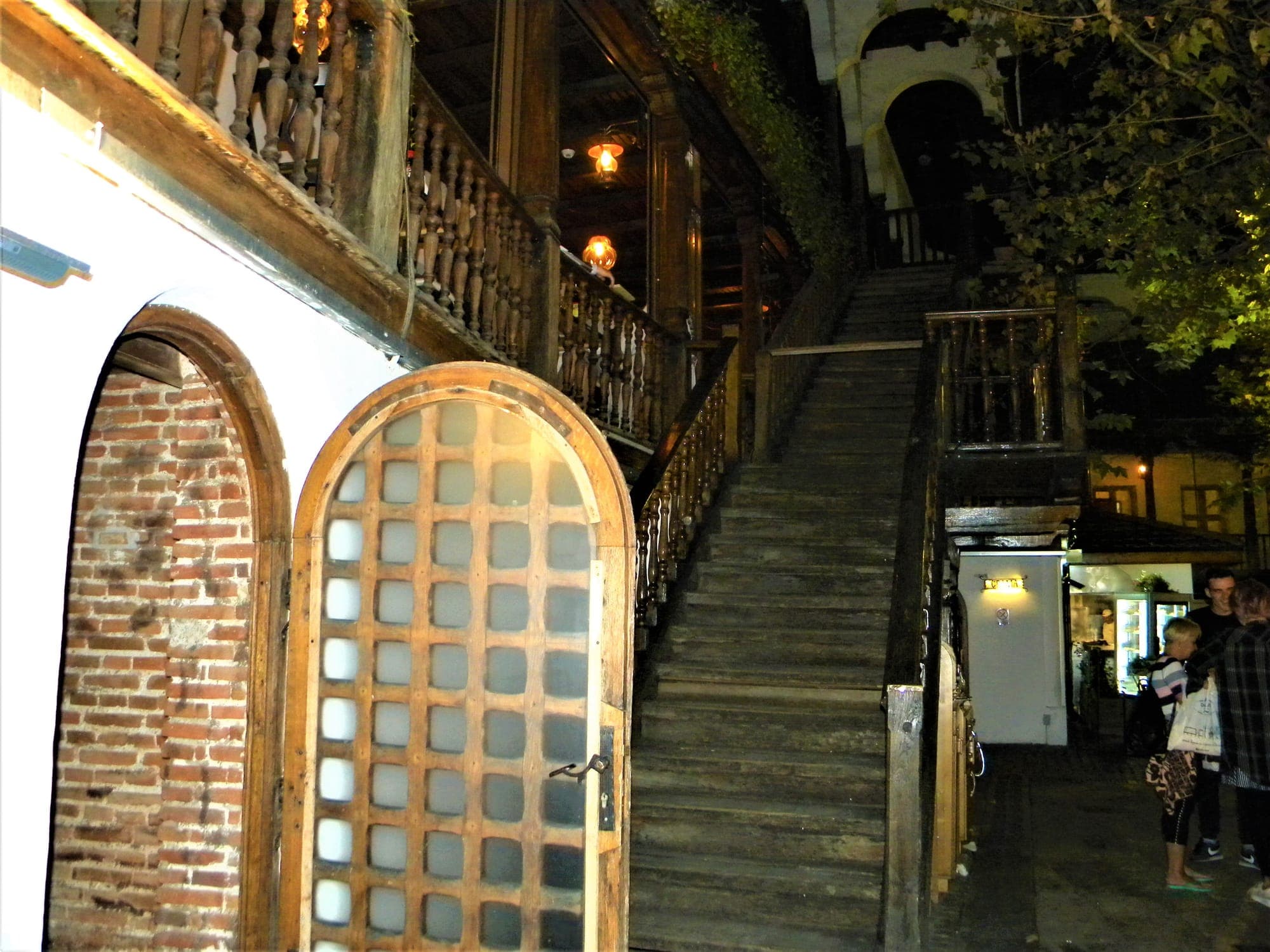 The wooden staircase and the gallery with its carved balustrade in the inn's inner courtyard, in the evening, with lanterns lit