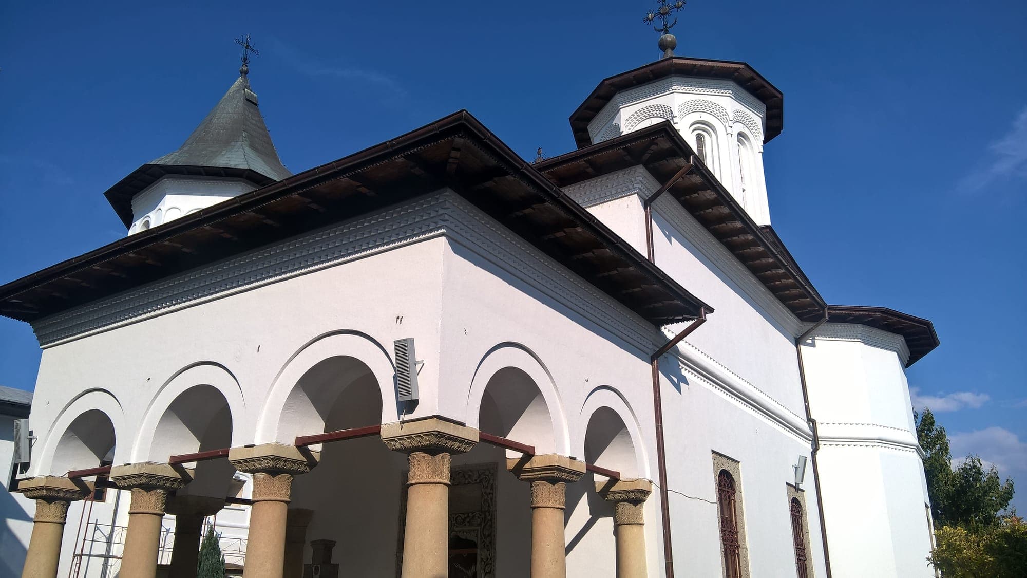 Die weiße große Kirche mit ihren Türmen und der Vorhalle auf Steinsäulen, von unten gesehen, unter klarem Himmel