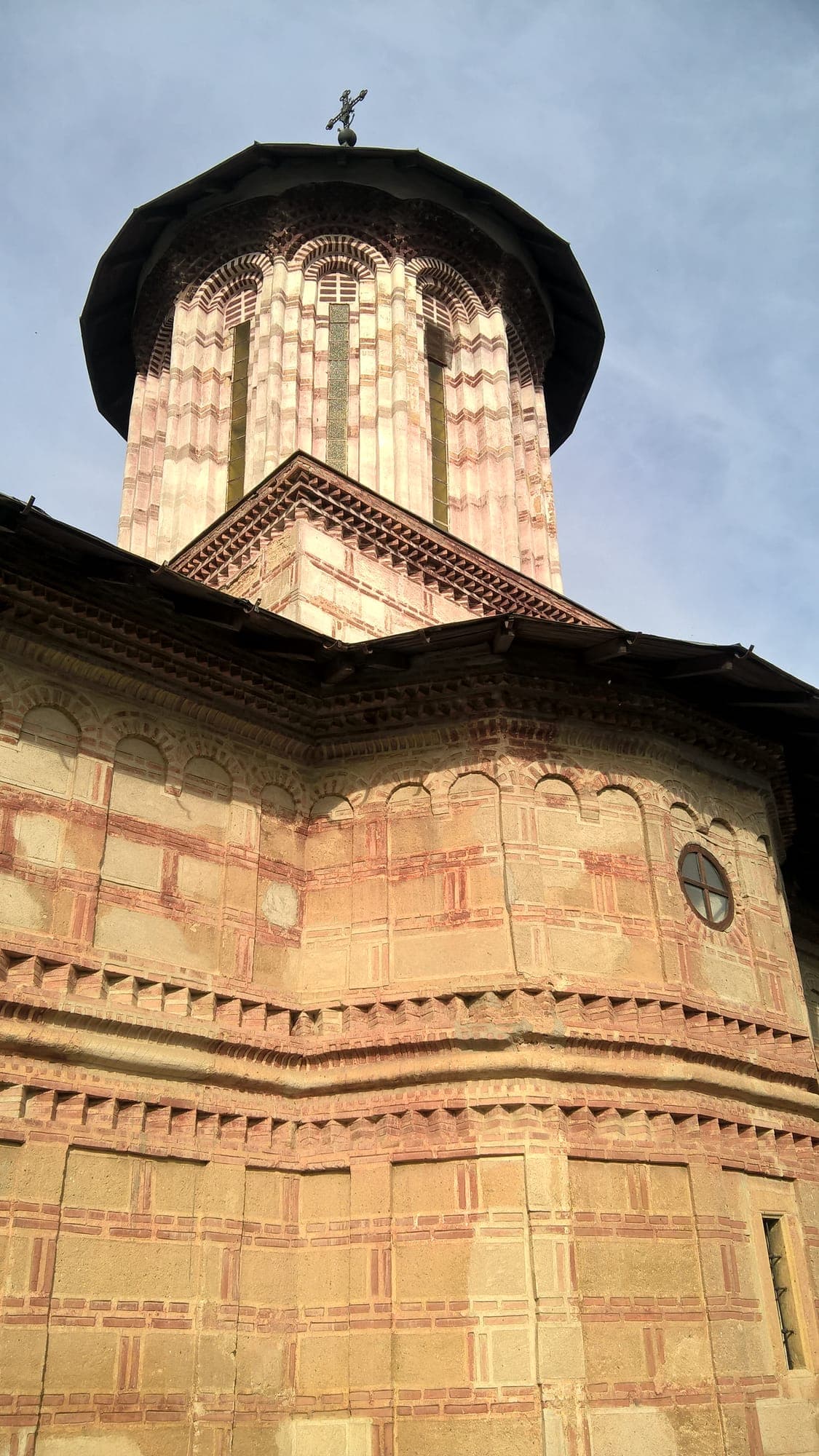 Turm und Apsis der Nikolauskirche mit Bändern aus Backstein und Stein und Bogennischen, von unten gesehen