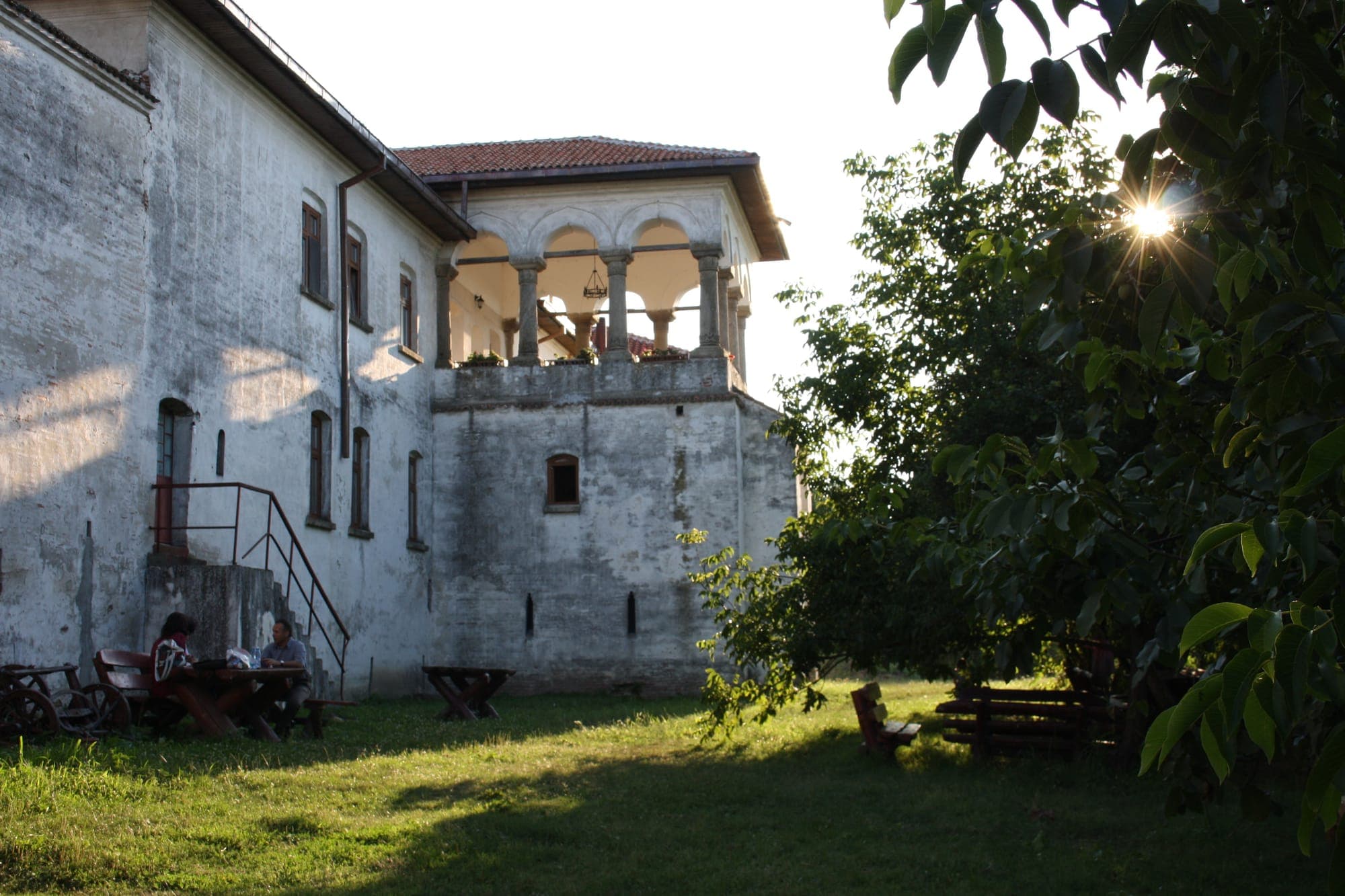 Foișorul cu coloane de piatră de pe latura de nord, deasupra zidului gros al incintei, văzut din iarba curții