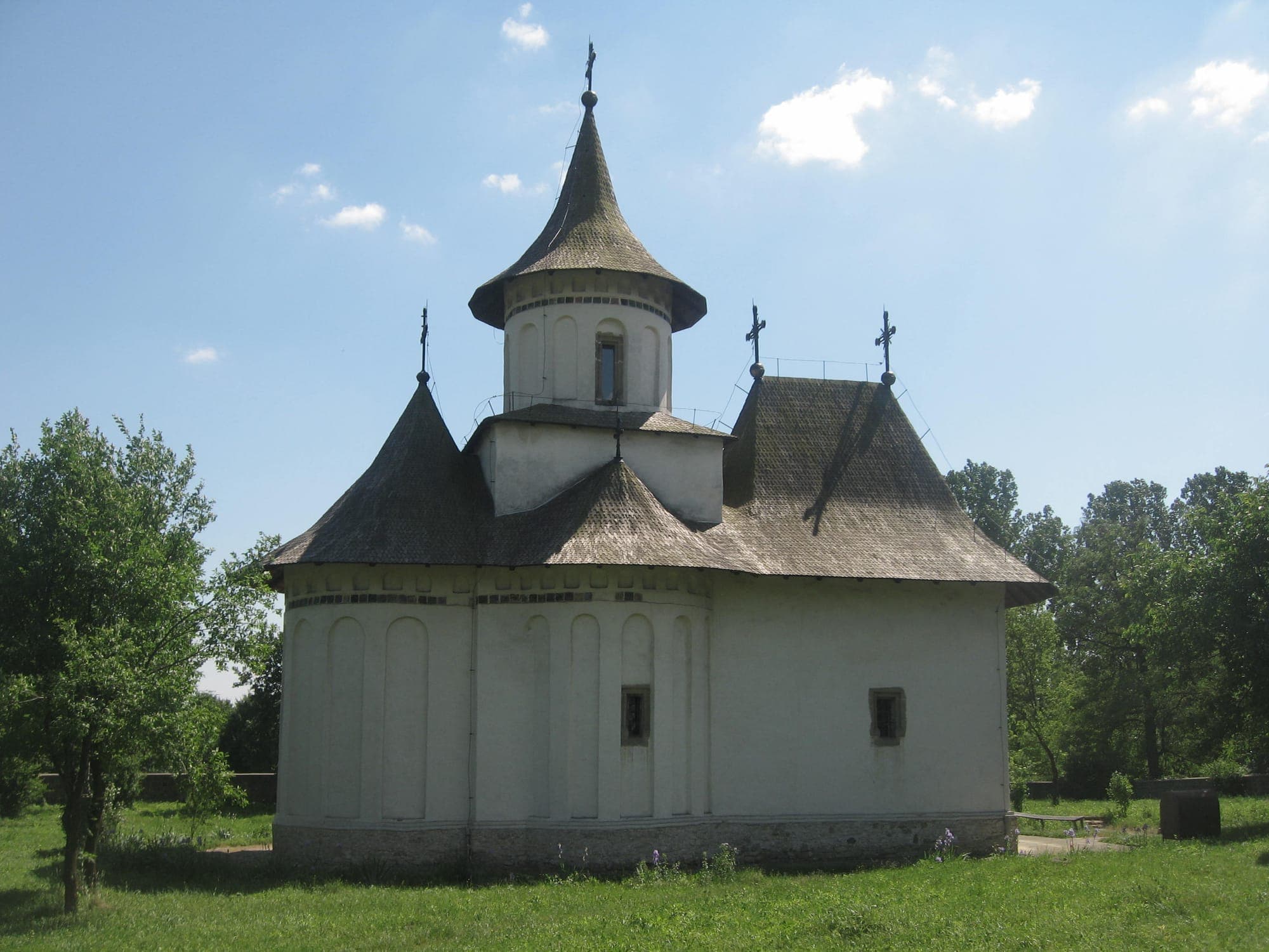 La chiesa vista da est, con le absidi dalle nicchie allungate, la torre slanciata e il cortile erboso