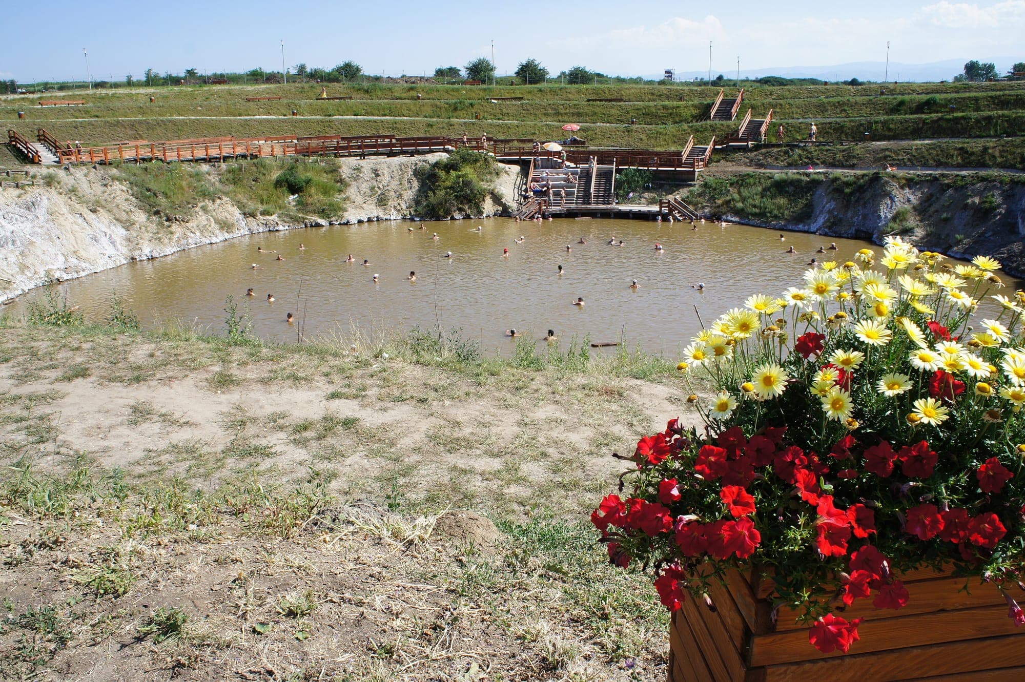 Lake Brâncoveanu, with its white salt banks, wooden walkways and steps leading down into the cloudy water, and a planter of flowers in the foreground