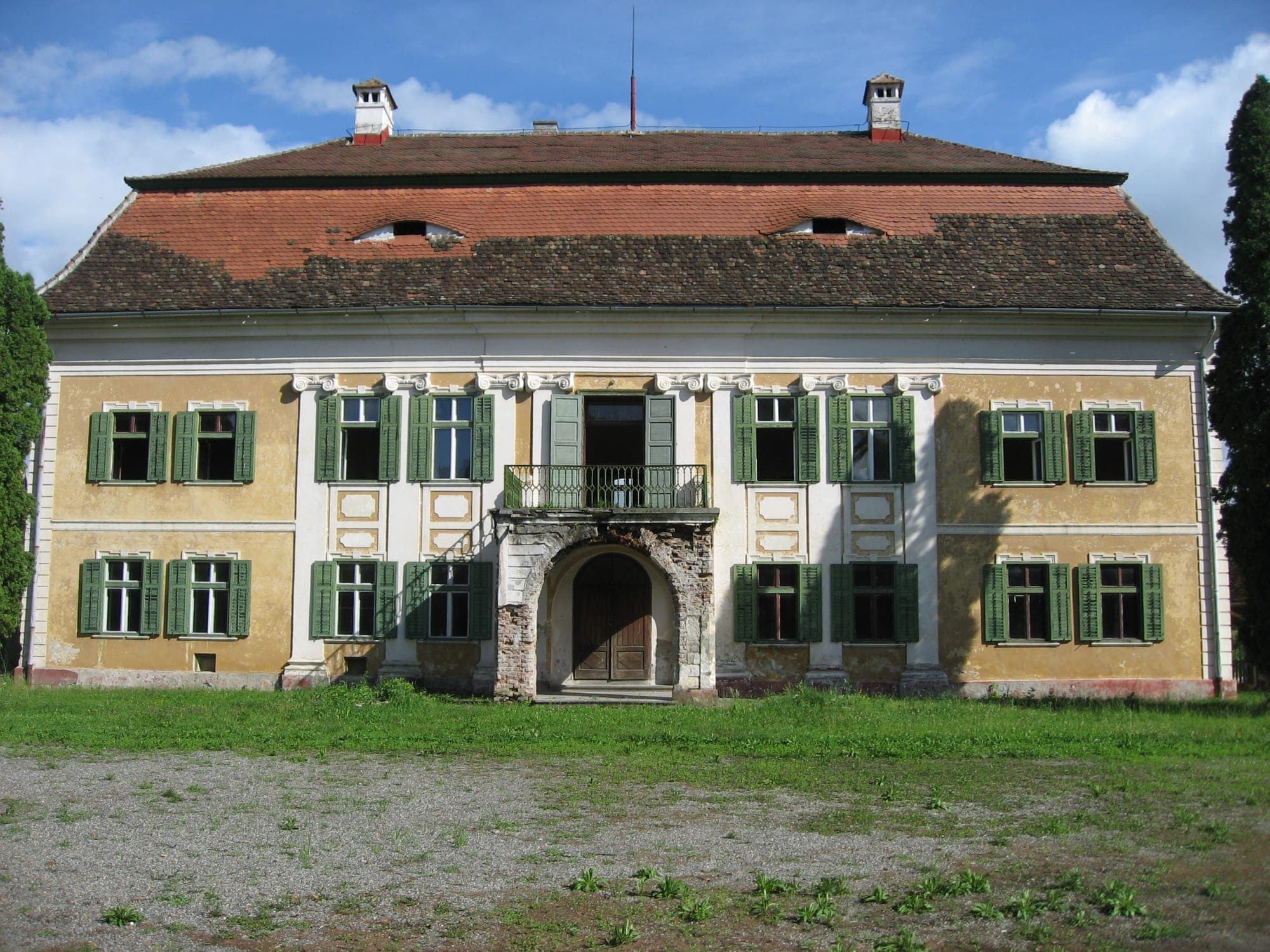 Die Hauptfassade des Schlosses mit schmiedeeisernem Balkon über dem Portal und grünen Fensterläden, vom Hof aus gesehen