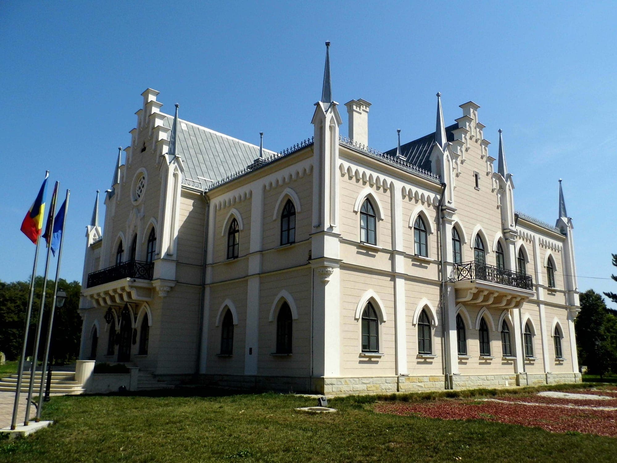 Palatul văzut din colț, cu frontoanele în trepte, pinaclurile și balcoanele de fier forjat, sub cer senin