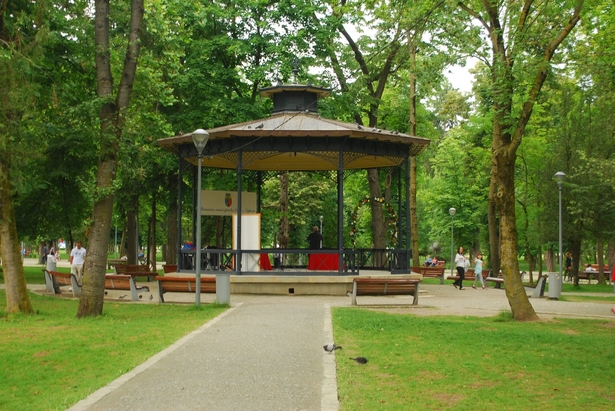 Il padiglione della musica con tetto di rame e ringhiera di ferro, tra gli alberi, con panchine davanti