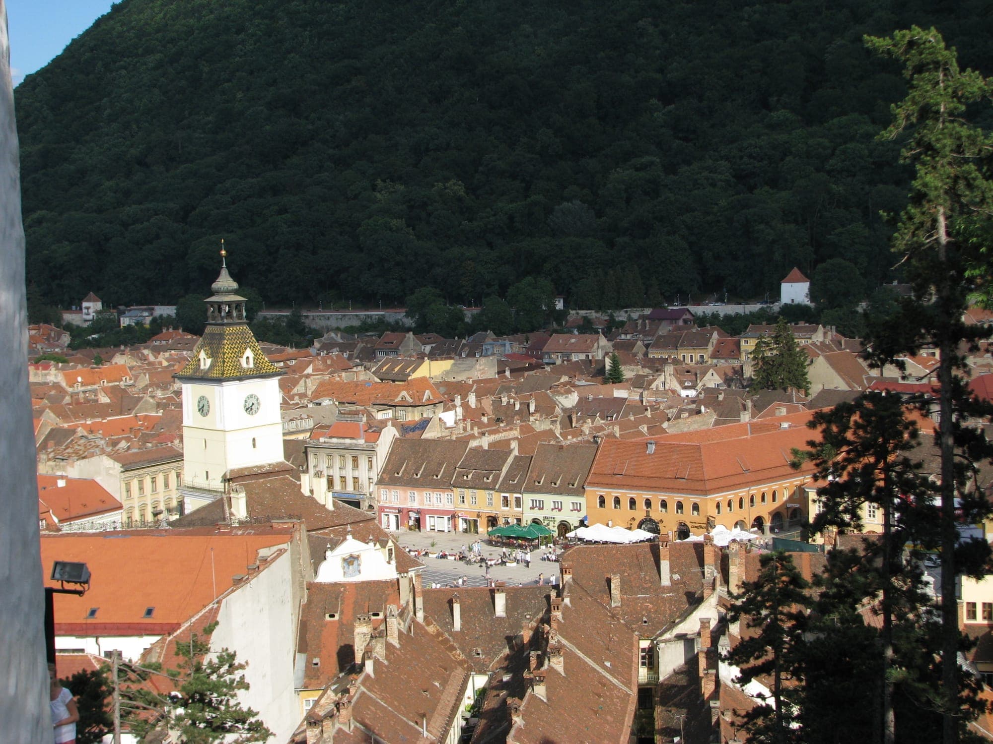 Die Altstadt vom Turm aus gesehen: rote Dächer, das Rathaus mit seinem Uhrturm und die Piața Sfatului, dahinter die bewaldete Zinne