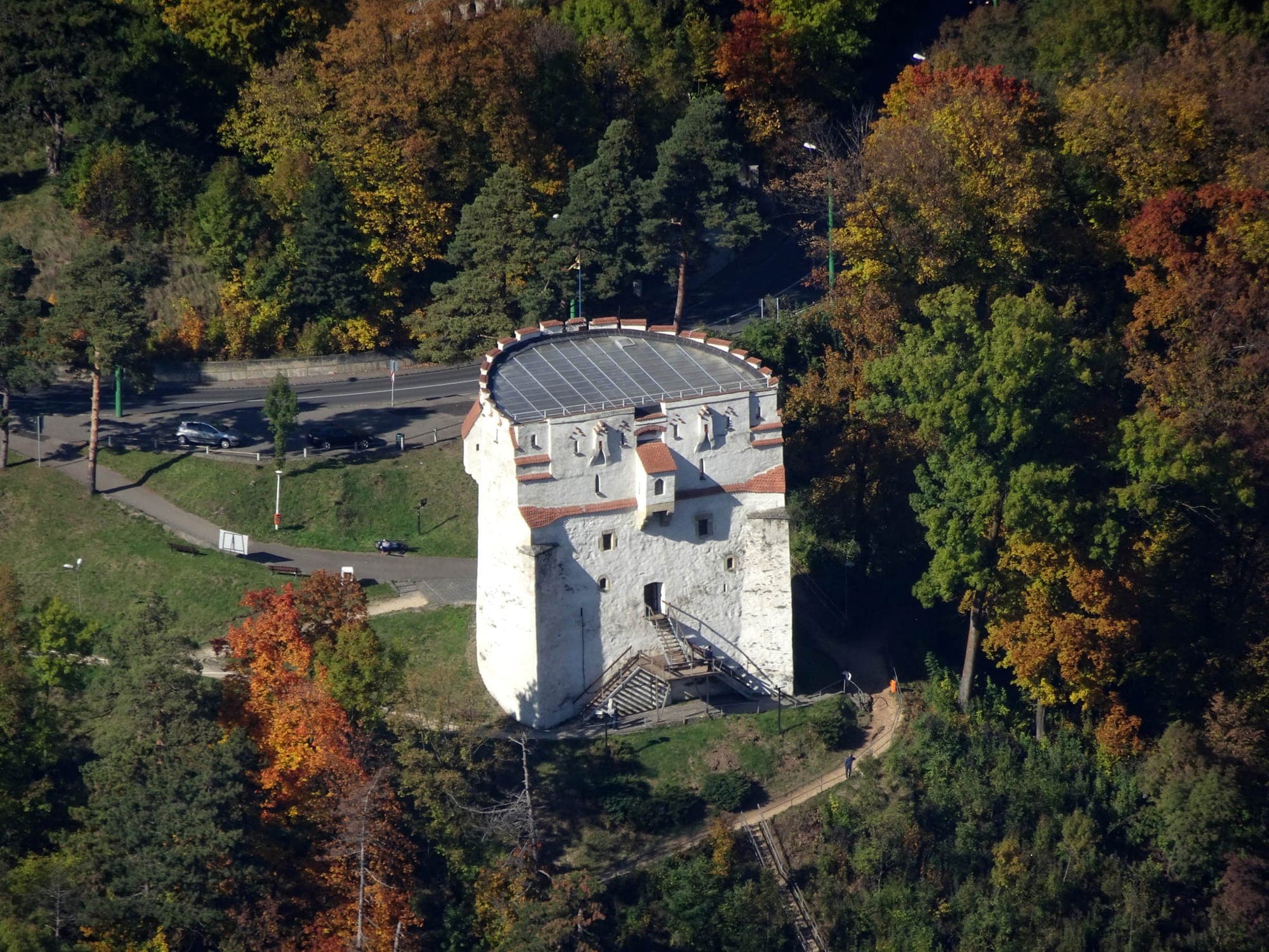 Der Turm im Herbst von oben gesehen, mit dem Glasdach über dem Innenhof, der steilen Treppe durch den Wald und der Calea Poienii darüber