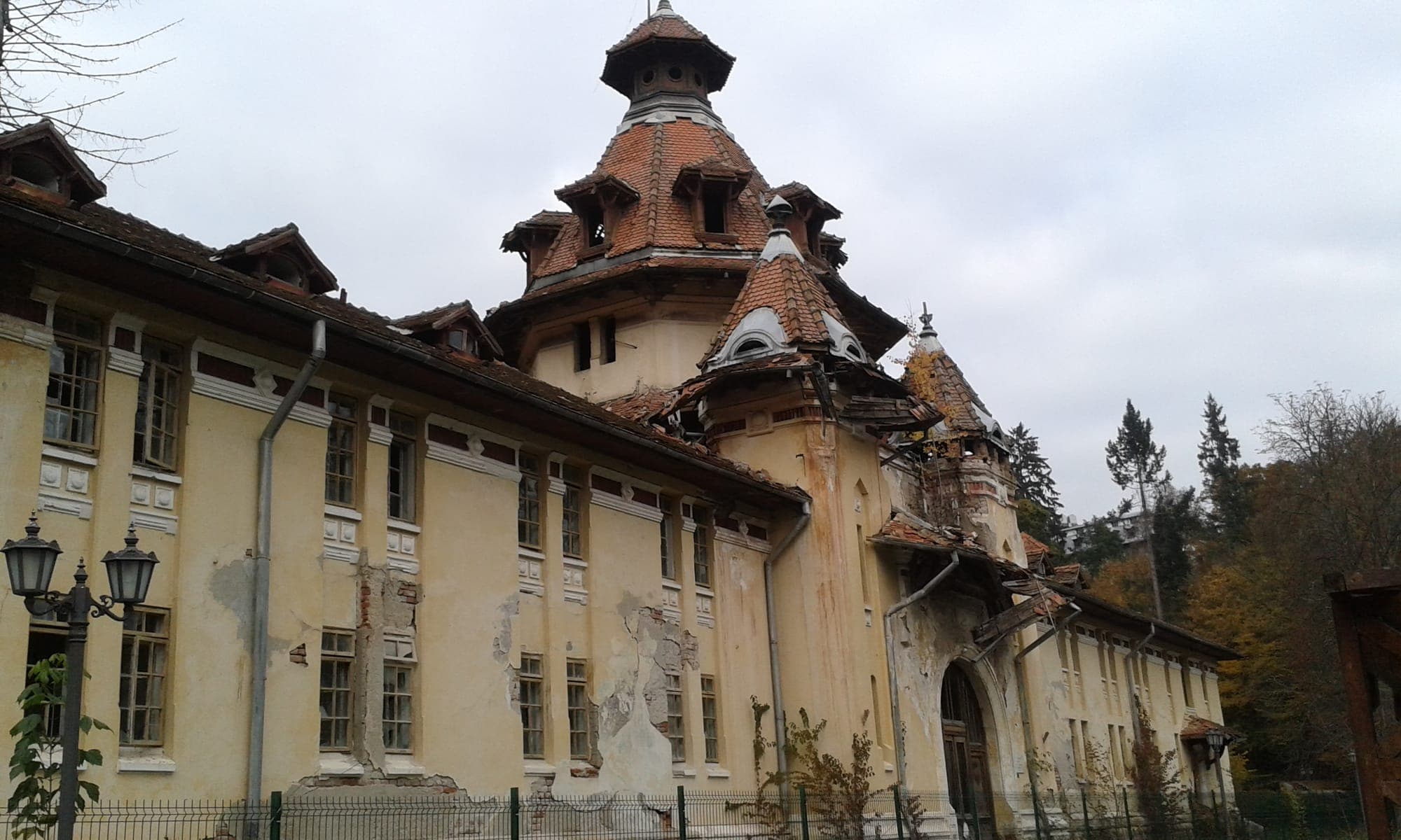 Pavilionul de băi, cu turnul central cu acoperiș în trepte și turnulețe, fațade galbene cu tencuiala căzută, într-o zi înnorată de toamnă