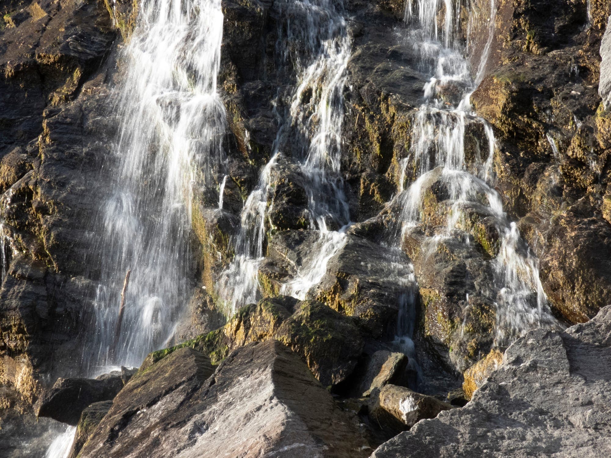 Cascada Capra căzând în mai multe șuvițe pe peretele de stâncă, în lumina caldă de după-amiază